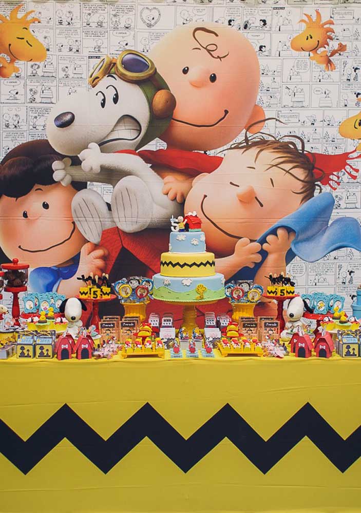 A panel made with the comics of the Snoopy gang frame this colorful and fun cake table 