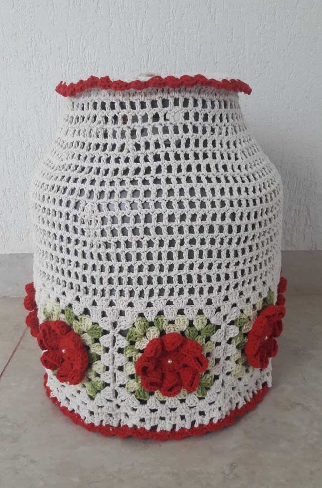 Crochet bottle cover made with string and red flowers to contrast 