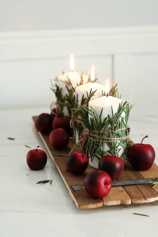 Look what an easier Christmas decoration: white candles with pine leaves tied by the jute cord. The wooden board with fruits completes the rustic proposal of the arrangement