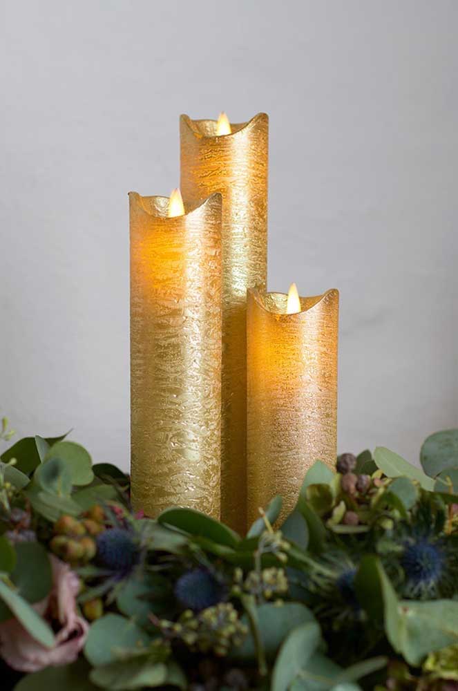 Golden Christmas candles surrounded by natural leaf arrangement