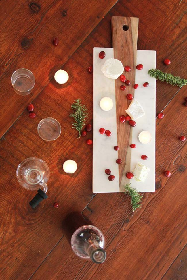 Natural Christmas table decoration with rosemary twigs, pomegranates, cheeses and candles