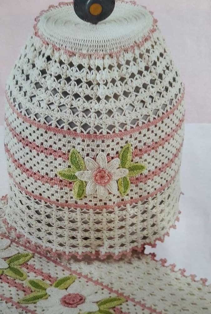 Crochet bottle cover made with string and red flowers to contrast 