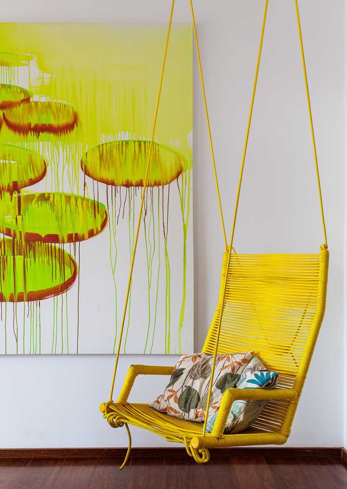 In this contemporary living room, yellow is present in elements of great visual appeal, such as the suspended armchair and the painting