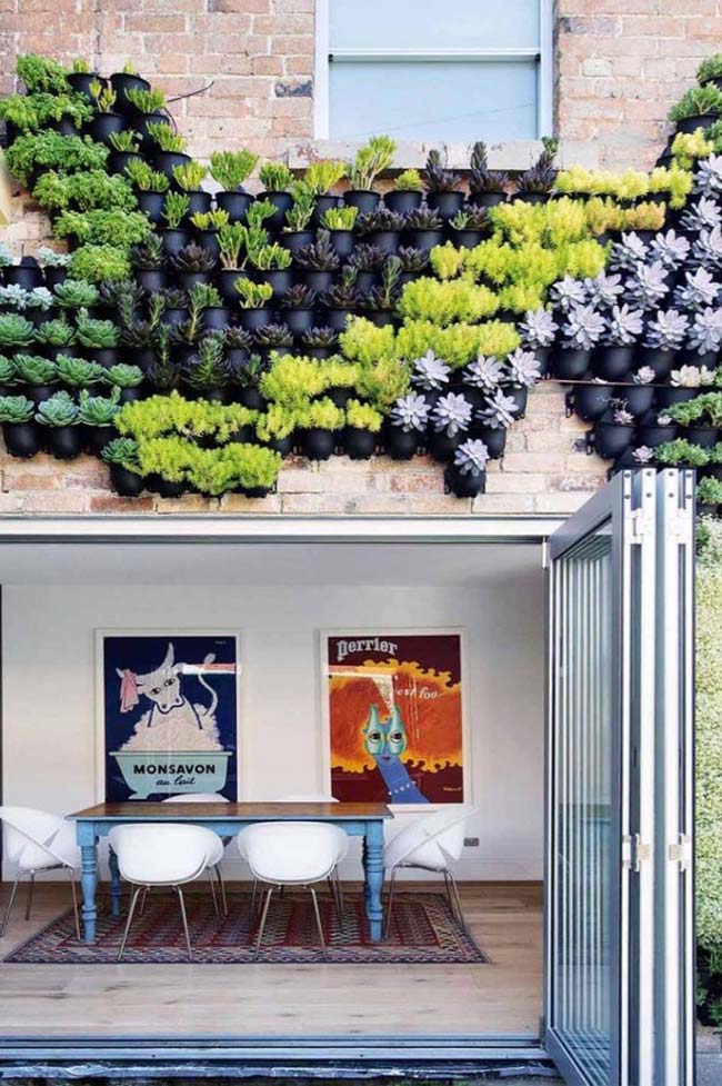 The facade of this house received pots of different colors and species to form the vertical garden