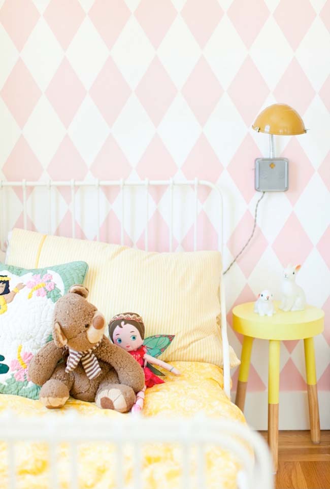 Girl's room with pink and white wallpaper with geometric shapes.