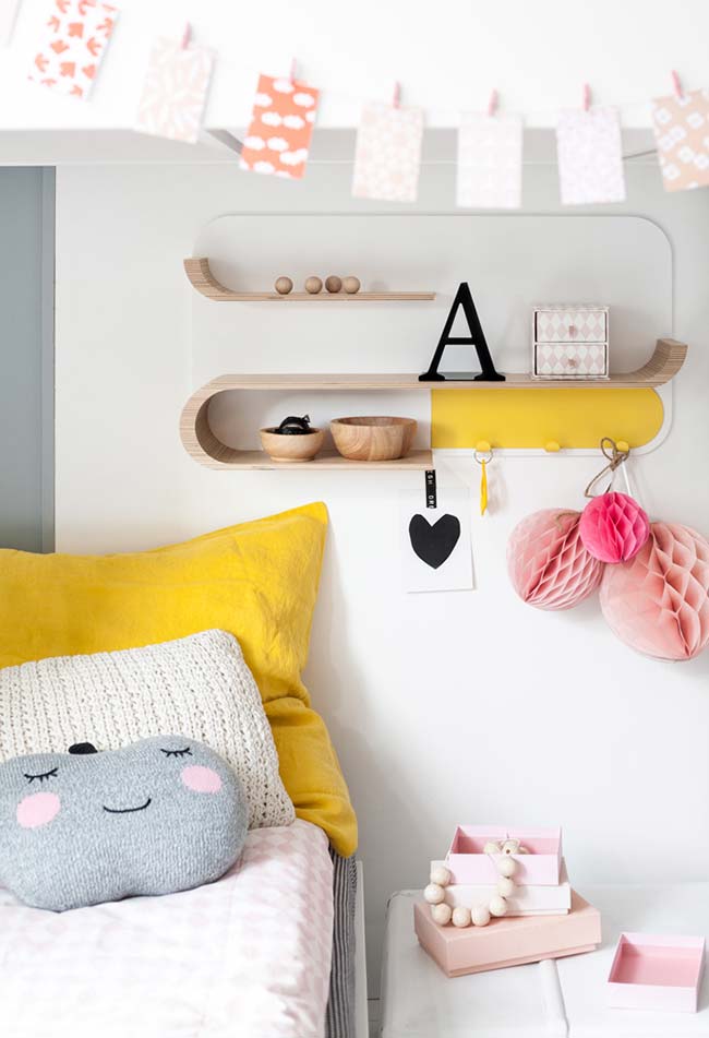 A super cute girl's room with curved shelf and bed with pillows