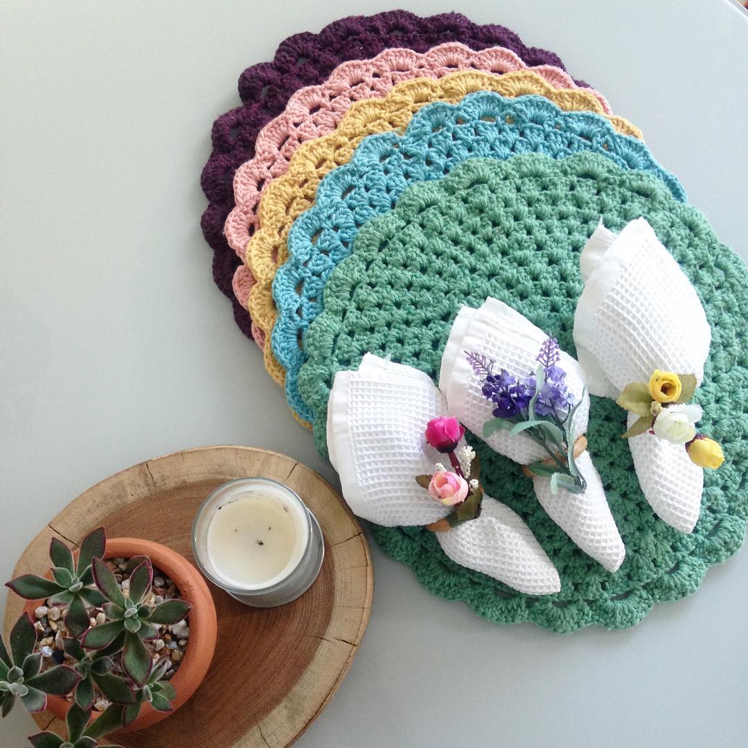 A multicolored set of crochet sousplats with purple, pink, yellow, blue and green water.