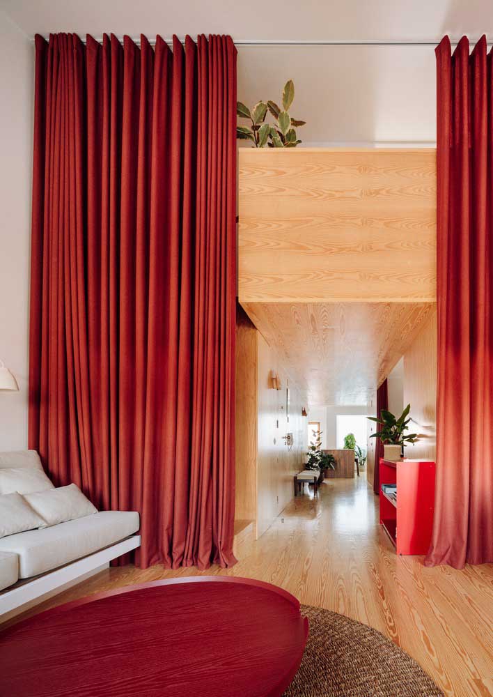 Room with red curtain that doubles as room divider