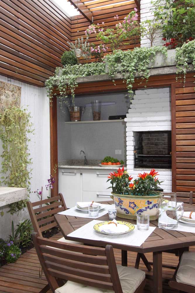 Beautiful reference of gourmet space with the brick barbecue painted in white color, perfectly matching the details in wood