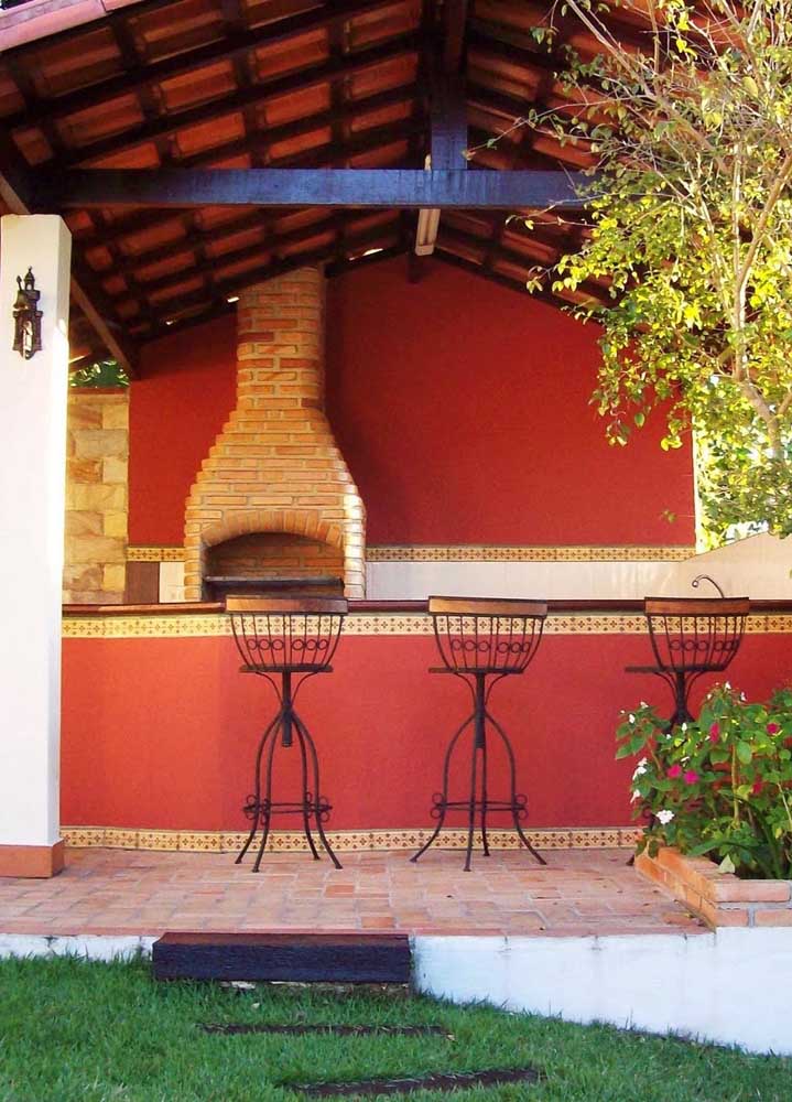 Gourmet space in rustic style with exposed brick barbecue and chimney with roof exit; the shade of red on the walls offers the cozy touch of the place