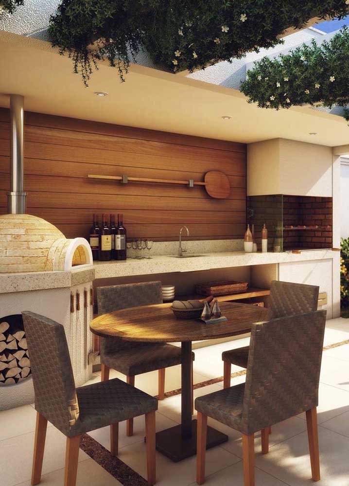 Masonry barbecue with wood oven and wooden panel in the background; the set creates a warm and cozy air for the gourmet space