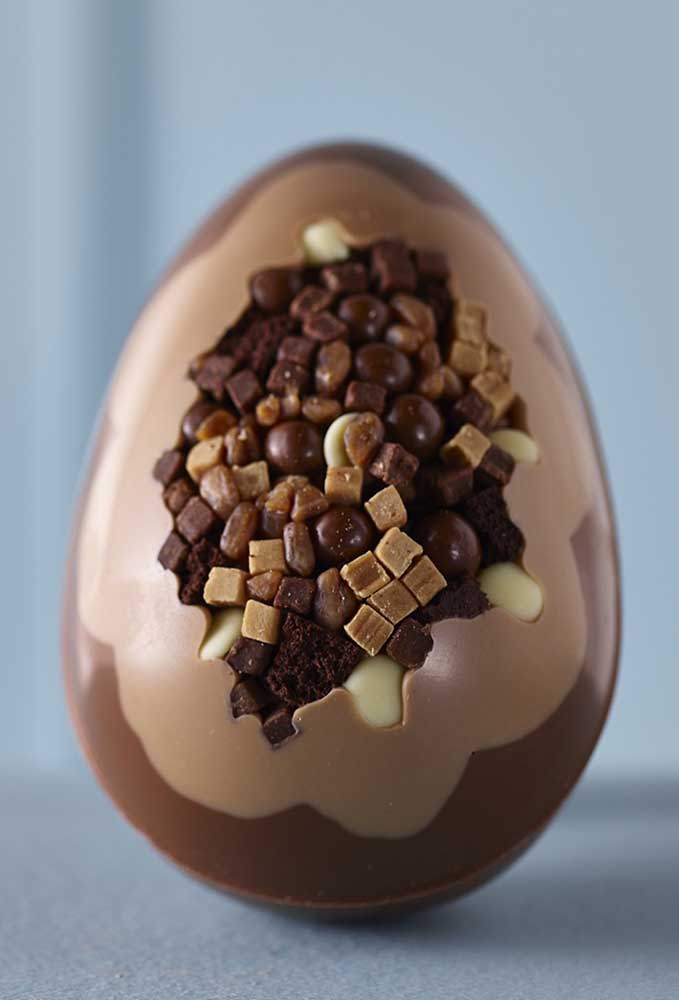 Chocolate Easter egg with pieces and balls of milk chocolate, semi-bitter and white chocolate in the center