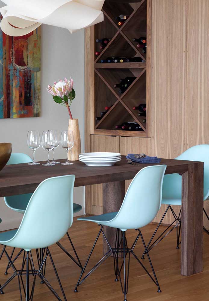 A mesa para sala de jantar de madeira rústica foi contrastada com as cadeiras modernas