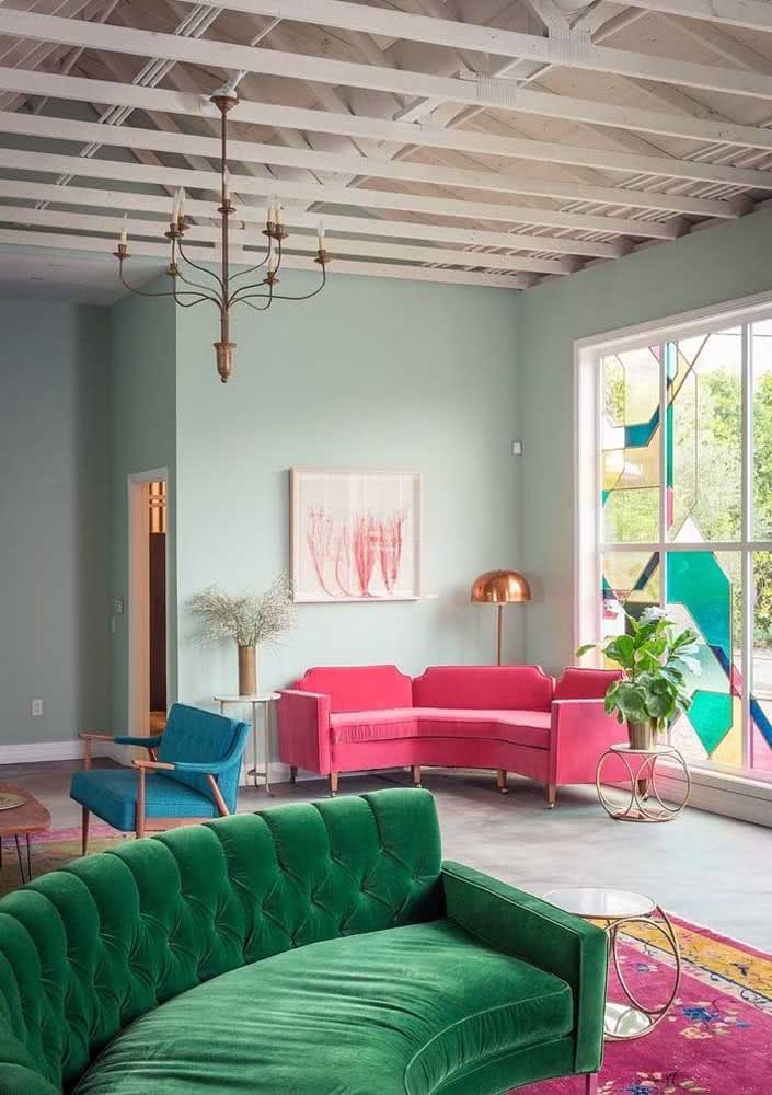Sofá rosa de canto formando um lindo conjunto visual com o sofá verde de veludo mais a frente