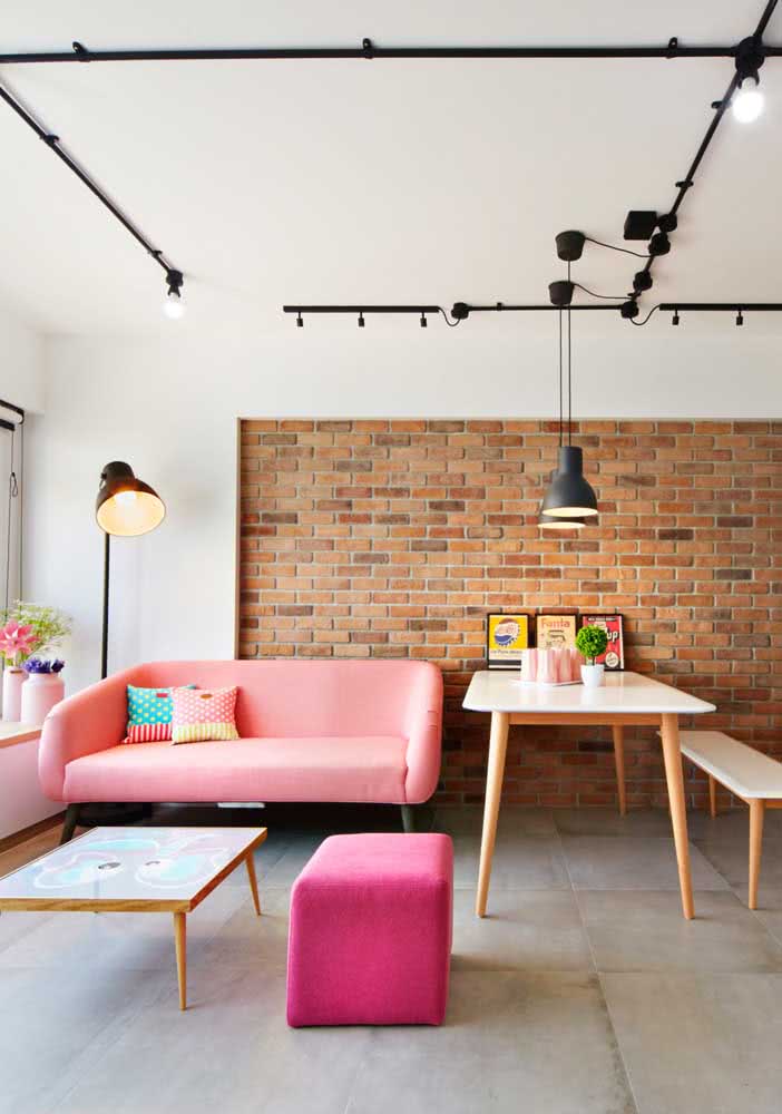 O sofá rosa fica incrível combinado com a parede de tijolinhos
