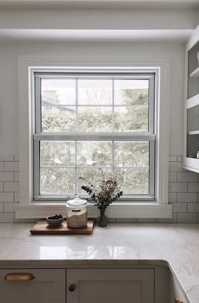 Janela guilhotina branca para combinar com a cozinha de azulejos, armários e mármore branco 