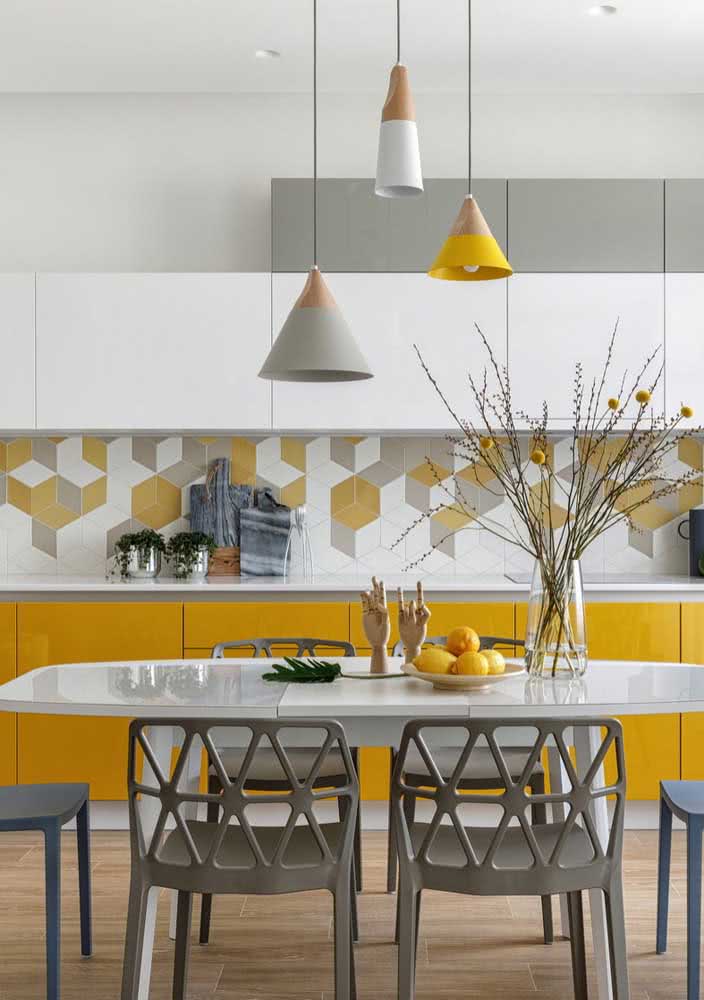 Cozinha amarela com toques de cor no revestimento, no armário e nas luminárias