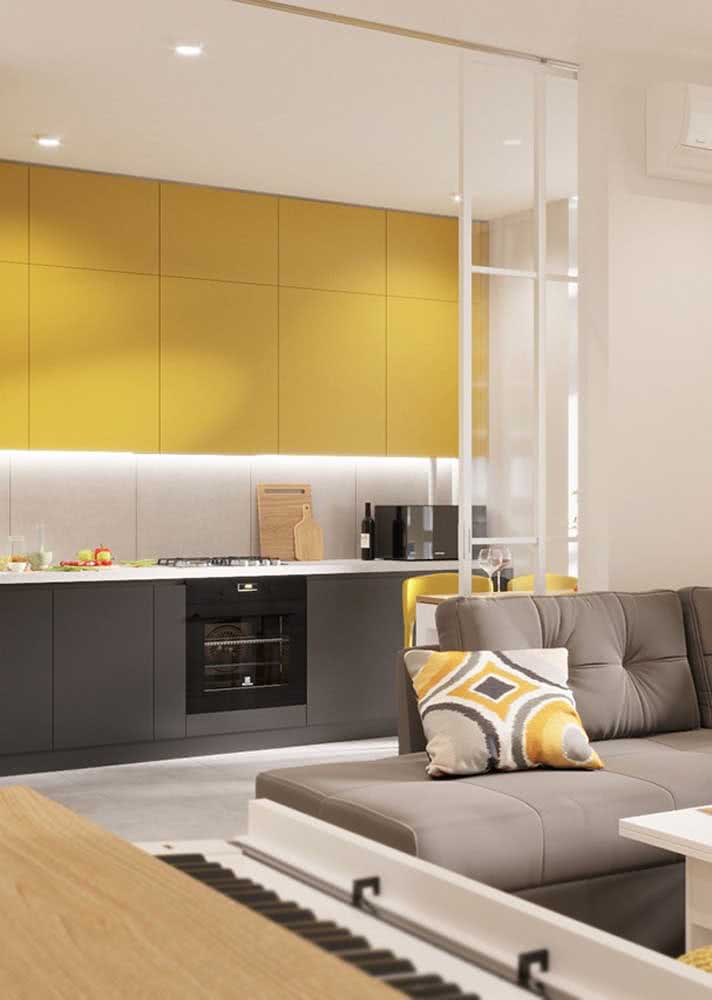 Cozinha amarela, branca e cinza integrada harmoniosamente com a sala de estar
